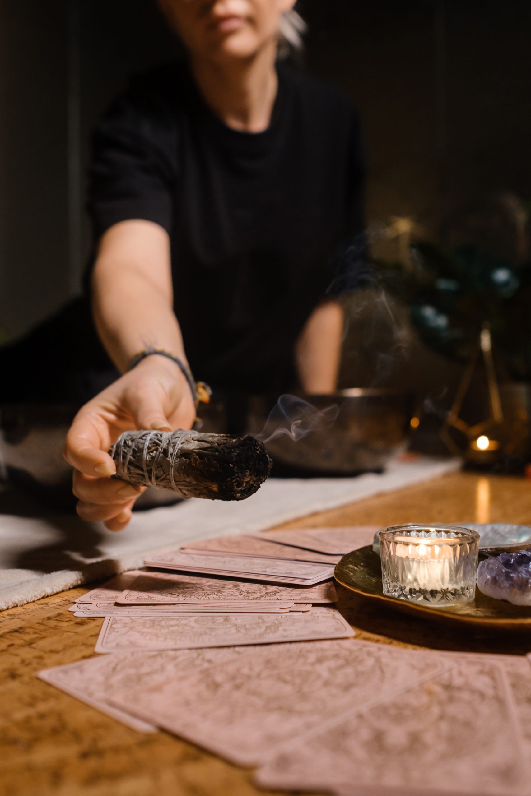 woman holding a smudge stick over tarot cards