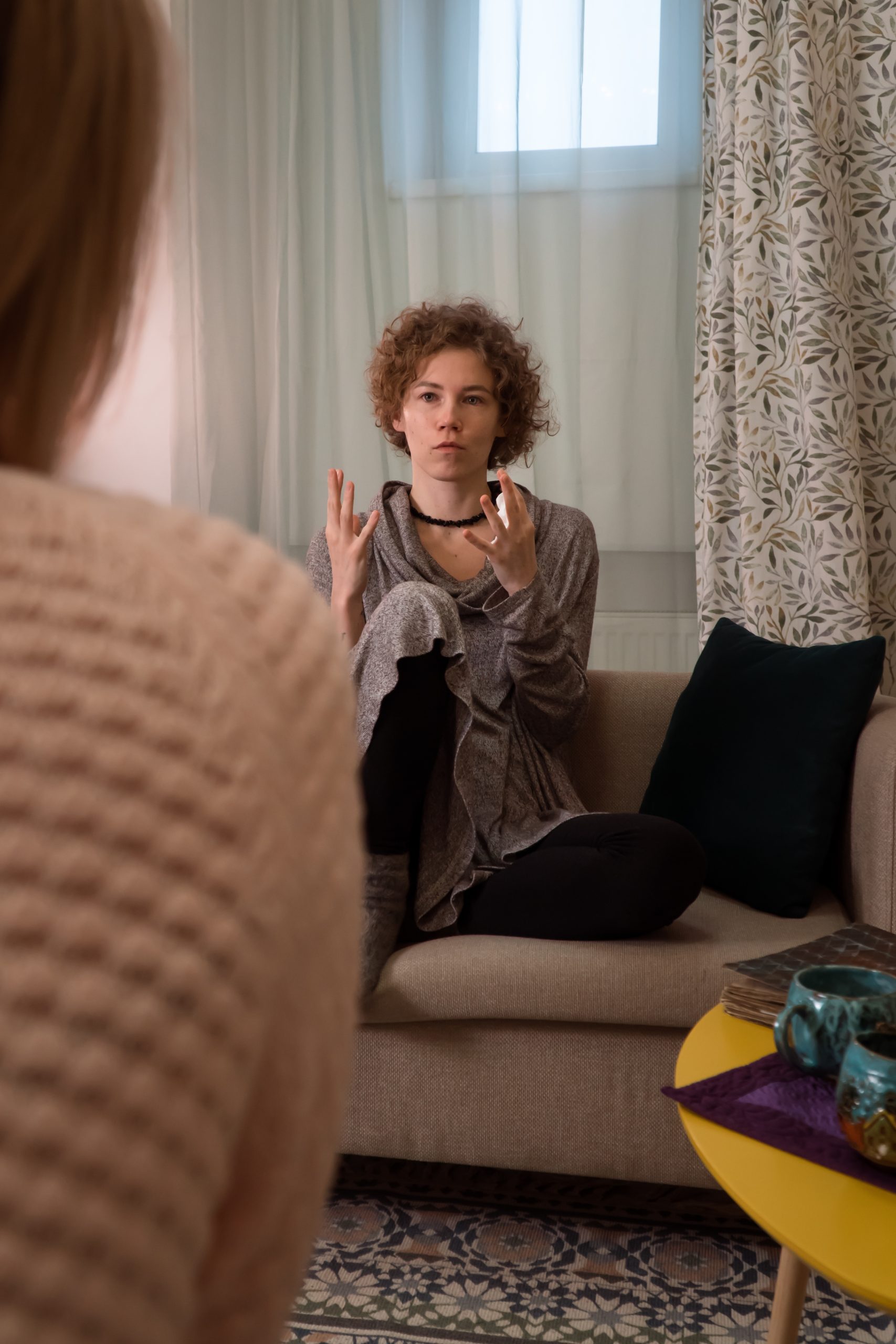 woman sitting on couch talking to another woman